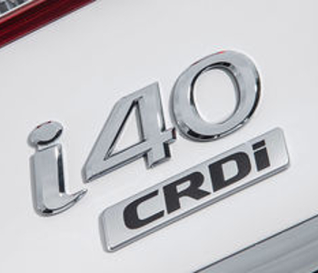 Close-up of a silver Hyundai i40 taxi badge featuring the i40 logo and a rectangular CRDi emblem in black letters on a white background.