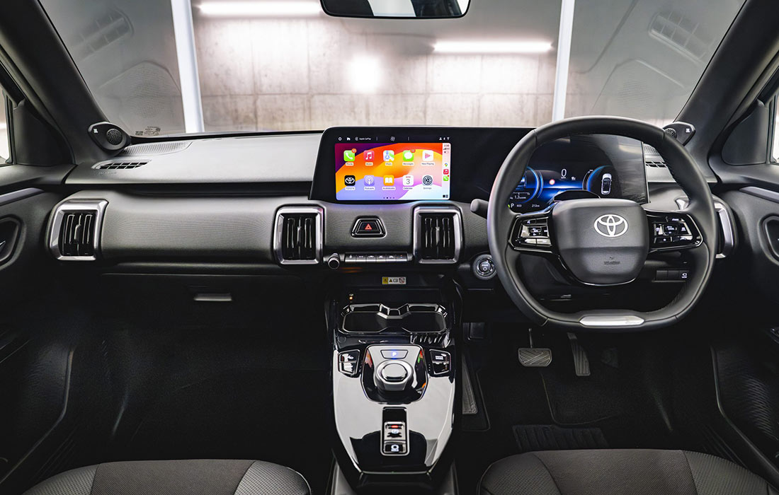 Modern Toyota taxi interior featuring a digital dashboard, large central touchscreen with smartphone app integration, and a sleek, glossy centre console. The steering wheel offers multiple controls for convenience. Clean, high-tech design ideal for professional taxi service.