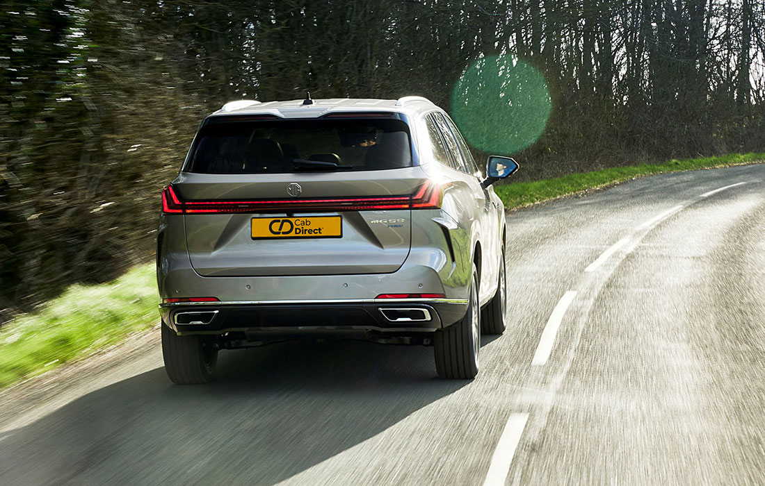 A silver SUV with a Cab Direct number plate drives along a scenic country road lined with trees and grass on a sunny day, ideal for taxi services.