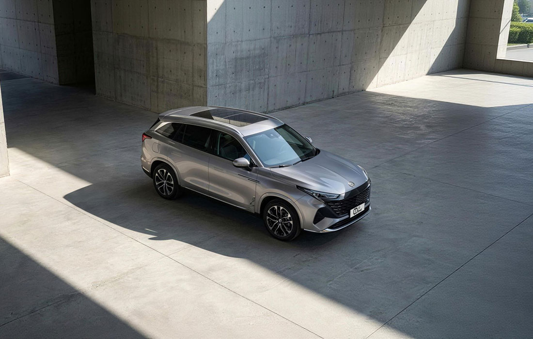 A silver SUV taxi is parked in a modern, open concrete structure with sunlight and shadows on the ground.