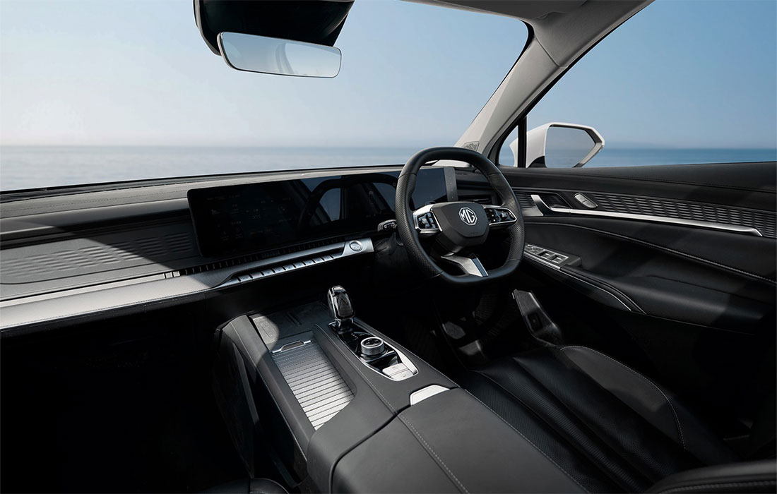 Modern taxi interior featuring a sleek black dashboard, advanced digital displays, leather seats, and a steering wheel, with a scenic ocean view through the windscreen.