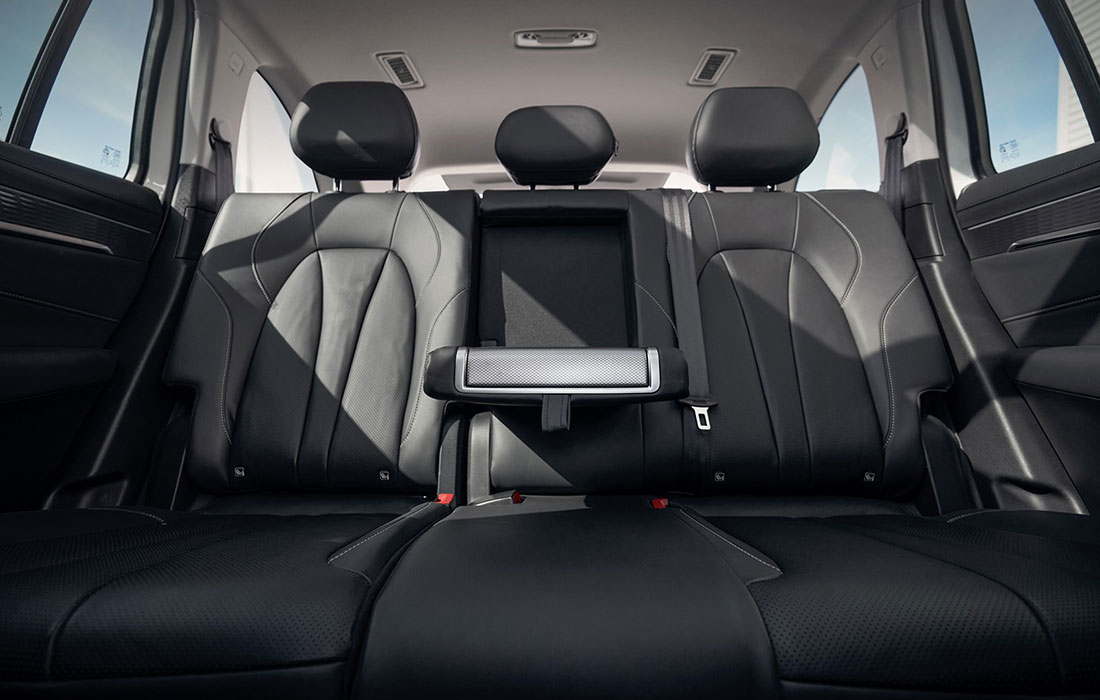 Spacious taxi back seat featuring three premium black leather seats, adjustable headrests, and a folded centre armrest for passenger comfort, viewed from inside the vehicle.
