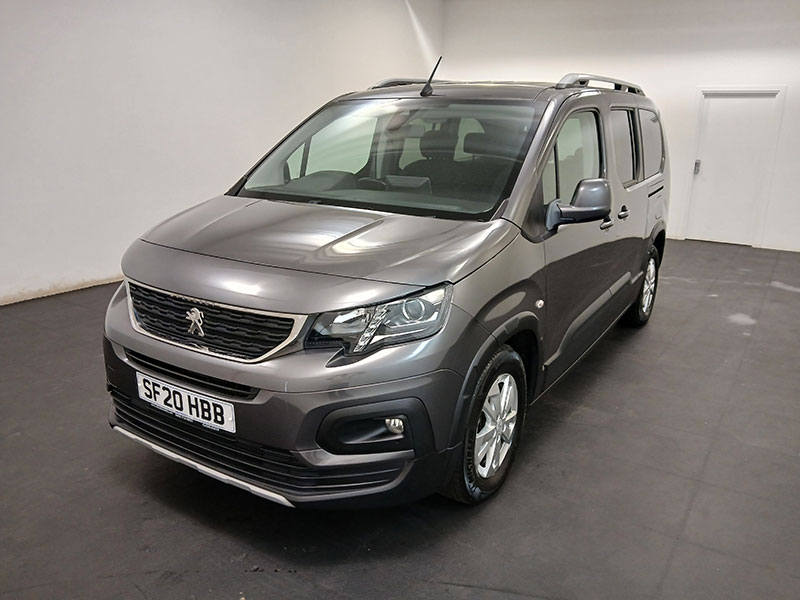 A silver Peugeot car with front number plate SF20 HBB is displayed in a clean, well-lit indoor showroom with white walls and a black floor. Ideal for taxi service.