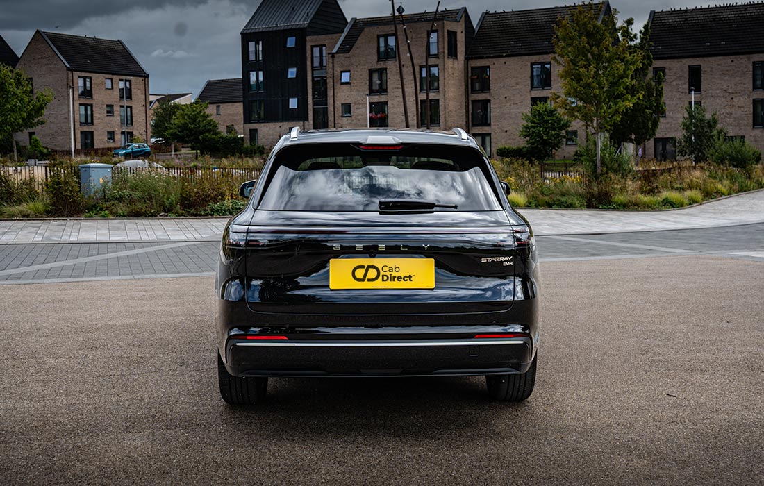 Black taxi with yellow Cab Direct plate parked on paved area in front of modern brick block of flats under cloudy sky. Perfect example of a reliable taxi for urban transport.