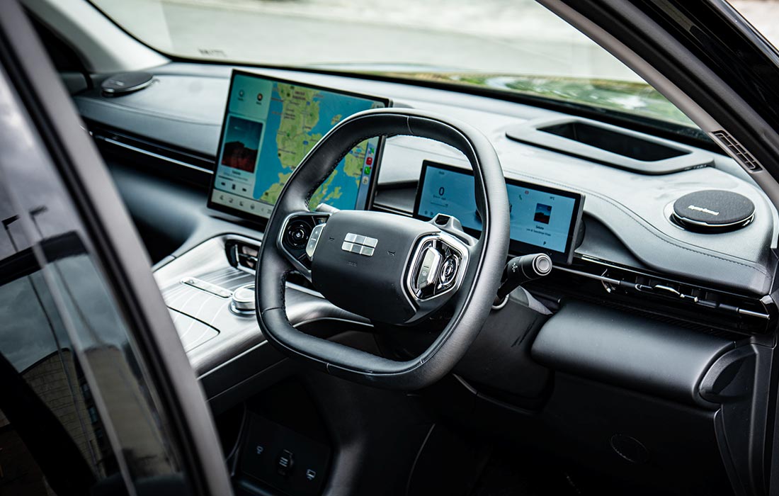 Taxi interior featuring a modern digital dashboard with three screens for navigation and passenger info, ergonomic steering wheel, and advanced, easy-to-use controls.