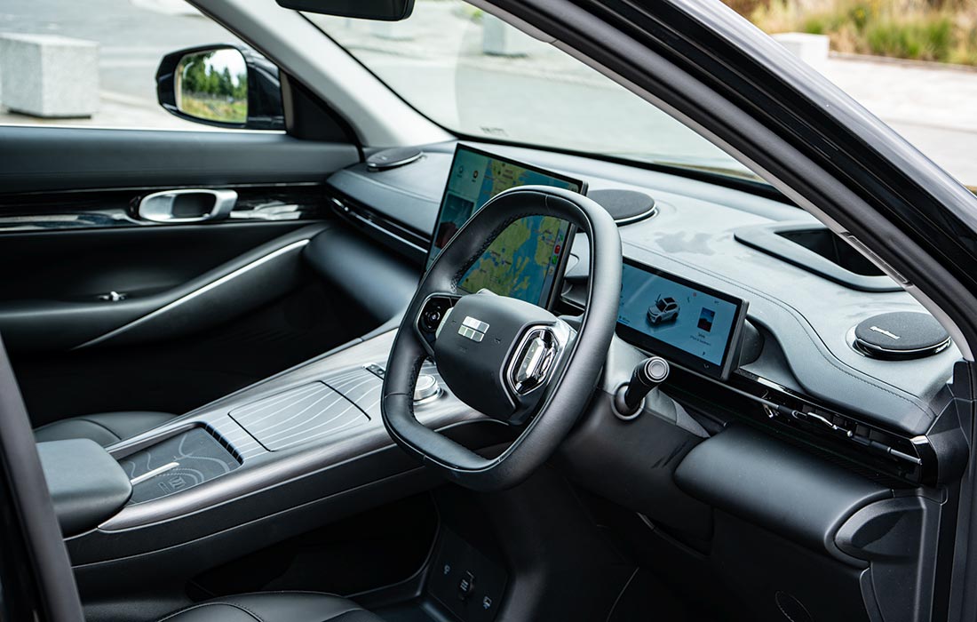 Modern taxi interior featuring a digital dashboard, steering wheel, and two large display screens. This right-hand drive taxi has sleek, high-tech seats and controls, ideal for professional drivers.