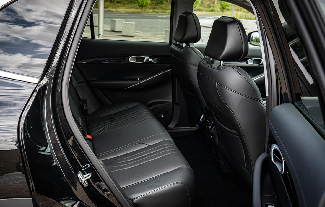 Rear passenger seats of a modern taxi with black leather upholstery, viewed from the open rear door. Interior is clean and well-maintained, ideal for commercial taxi use.