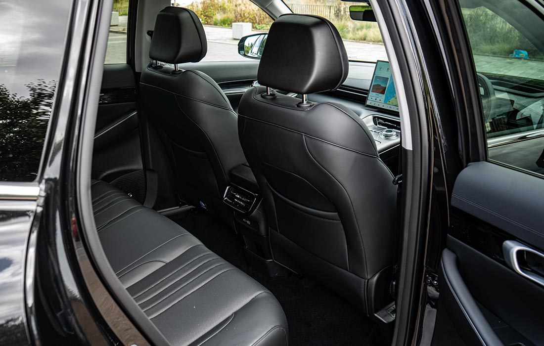 Interior view of a taxi showcasing spacious rear seats and front seat backs with premium black leather upholstery, a dashboard-mounted infotainment screen, and an open car door. The clean, modern cabin highlights comfort and style—ideal for taxi services.