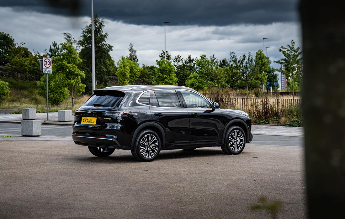 A black SUV taxi is parked in an empty car park near greenery and a 30 km/h speed limit sign under a cloudy sky.