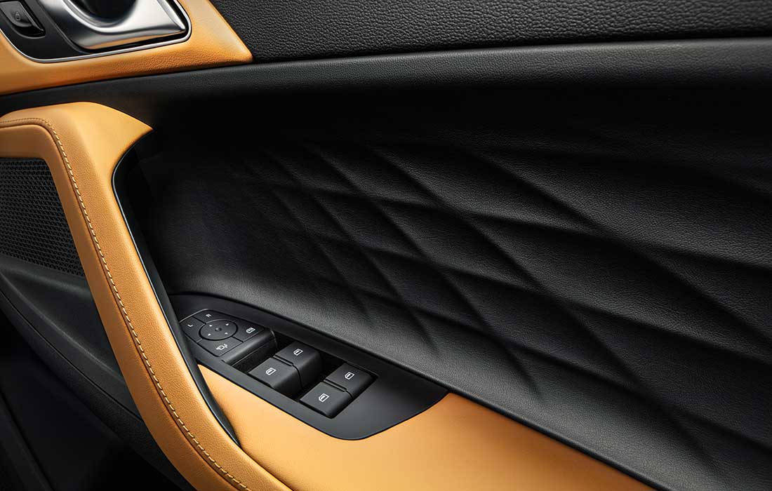 Quilted black taxi door panel with tan trim and electric window controls.