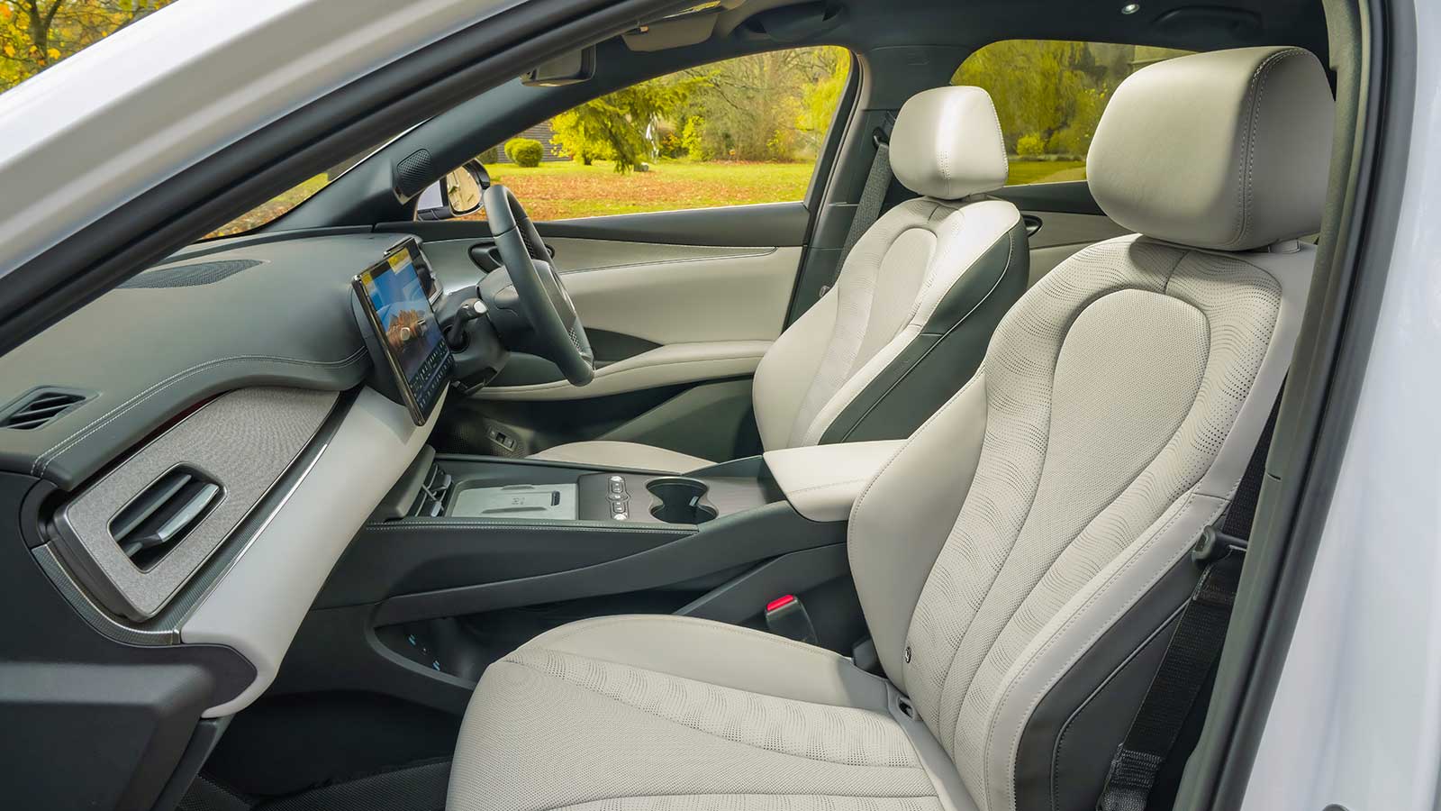 Modern taxi interior featuring light-coloured leather seats and a digital dashboard display.