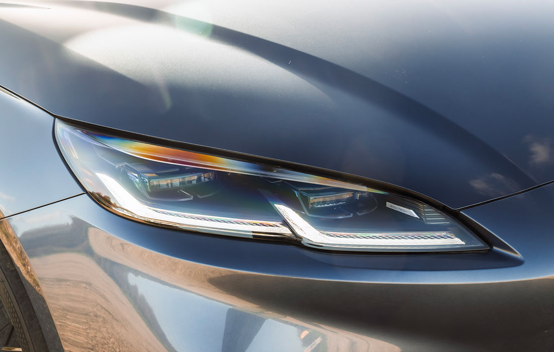 Close-up of the front headlamp of a grey Ford taxi.