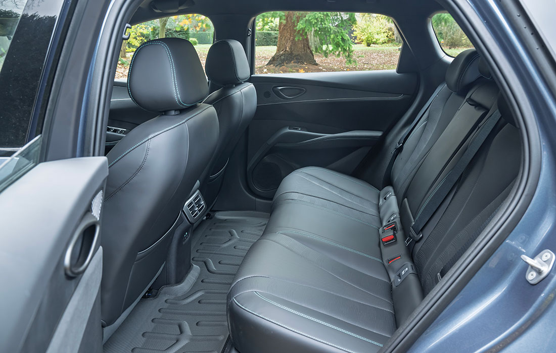 Spacious interior of a dark blue taxi featuring black leather upholstery and durable rubber floor mats.