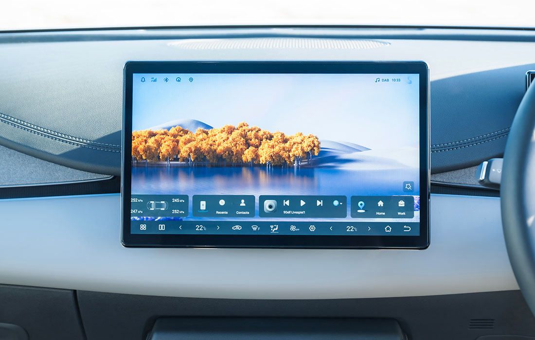 Infotainment touchscreen display in a taxi featuring a landscape wallpaper and climate control settings.