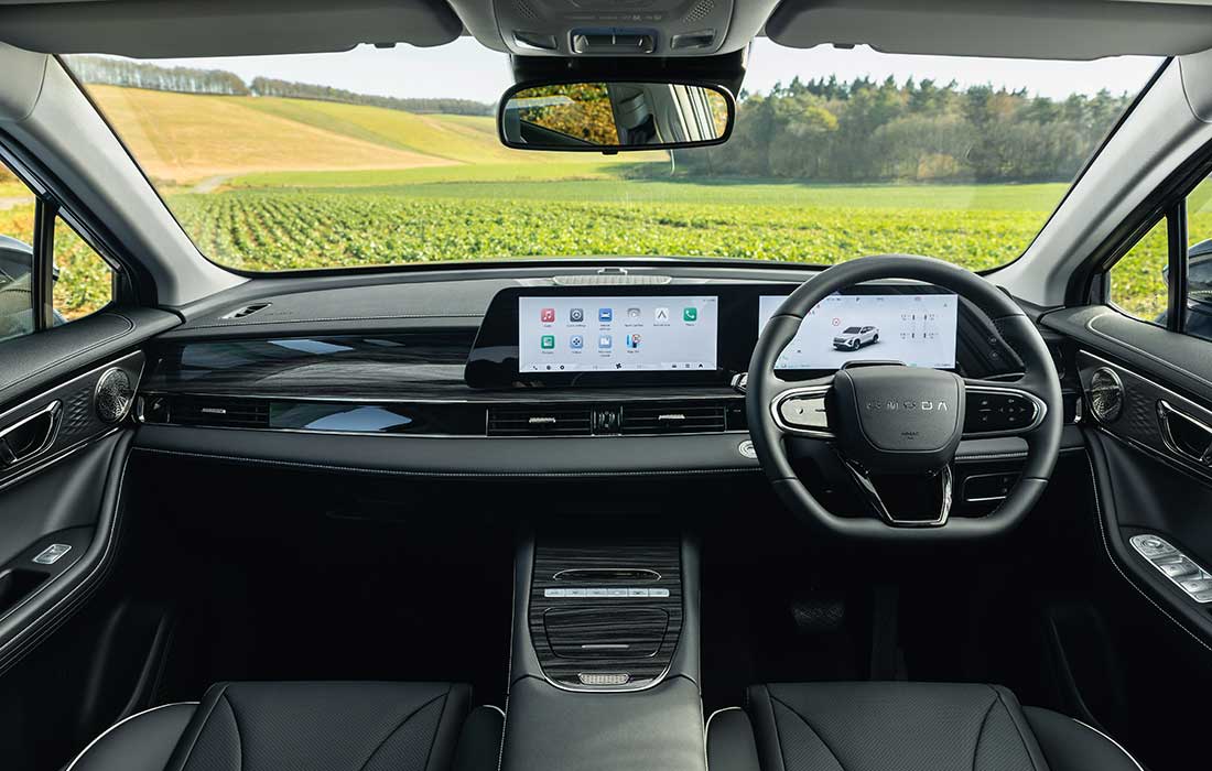 Driver’s perspective of a Škoda taxi interior featuring a digital dashboard and steering wheel overlooking a rural landscape.