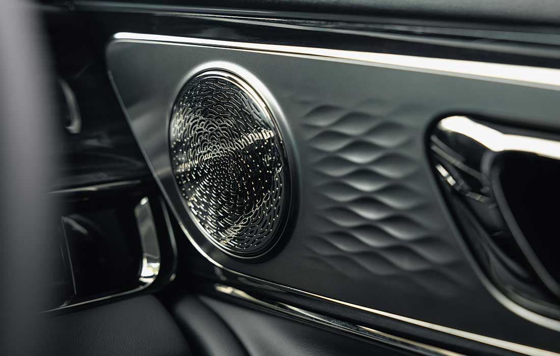 Close-up of a circular metallic speaker grille on the interior door panel of a taxi.