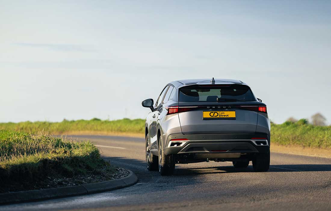 Silver Omoda 5 taxi driving on a countryside road.